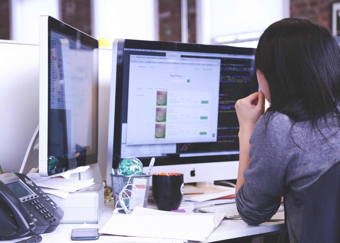 Programadora a trabalhar num site em dois ecrãs
